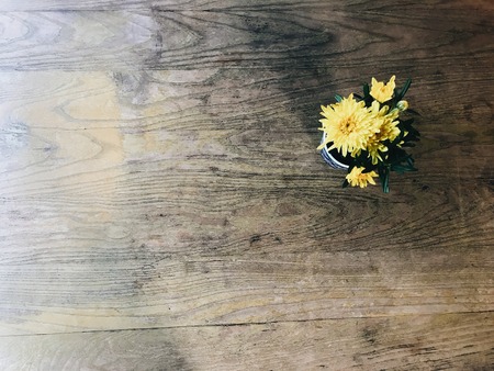 Top view of yellow flowers in a vase on a wood table, with copy spaceの写真素材