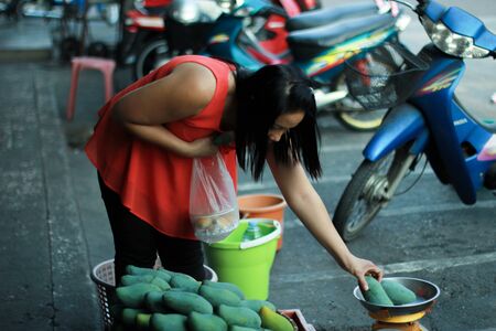 Nakhon Pathom/Thailand - March 25 2016 : A middle-age woman choosing mangos to buyのeditorial素材