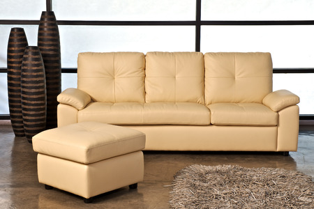 Beige leather sofa with stoolの写真素材