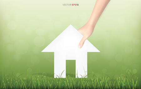 Hand pick paper house on green yard area. Conceptual image of real estate idea. Vector illustration.のイラスト素材