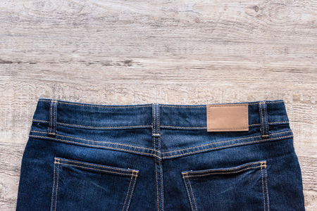 Blue jeans on wood background with brown leather label.の写真素材