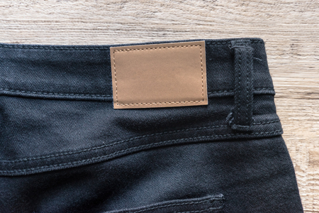 Back of jeans on wood background with brown leather label.の写真素材
