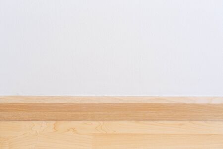 Wooden wall base skirting, finishing material with wood laminate floor and white mortar wall. Empty room with white wall and wooden floor new clean modern design.の写真素材