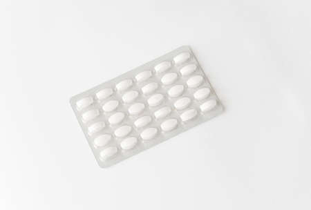 White pills tablets in package on a white background. Capsule pills in plastic pack for pharmacy and...