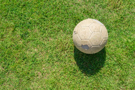 Old soccer ball on green grass of soccer field. Vintage football.の写真素材