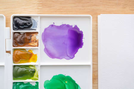 Watercolor paints in watercolor palette white paper. Bright multicolored aquarelle paints in paint...