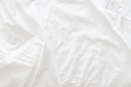 Abstract background of rippled white silk fabric, white fabric draped in soft waves empty bed sheet. Close up.の写真素材