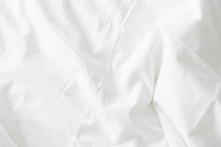 Abstract background of rippled white silk fabric, white fabric draped in soft waves empty bed sheet. Close up.の写真素材