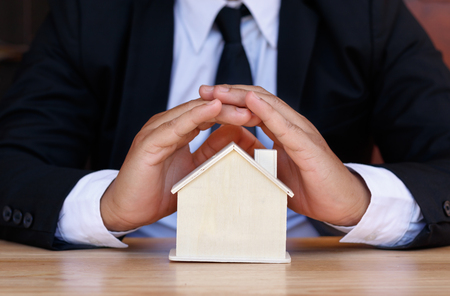 Businessman hands protect small house. home insurance conceptの写真素材