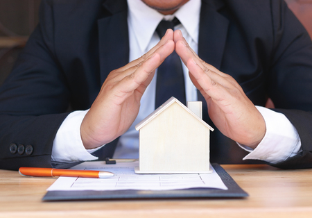 Businessman holding small home. Home insurance concept.の写真素材