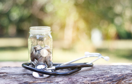 Coin and stethoscope on wooden background.の写真素材