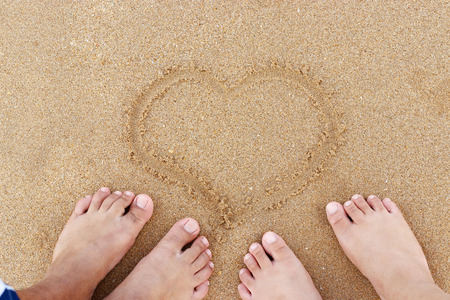 Beach couple in love with heart on sand background. summer, happy weekend concept.の写真素材