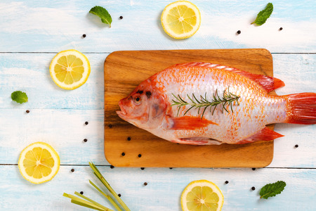 Top view of fresh fish, lemon,black pepper and rosemary on blue background.の写真素材