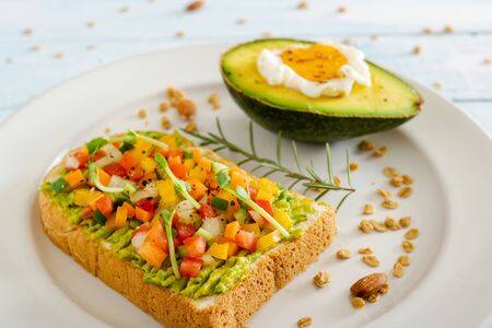 Fresh breakfast to consist of healthy toast with avocado,egg, almond, pea sprouts,cereal,radish and rosemary on blue wooden background.の写真素材