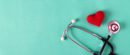 Heart made of red yarn with stethoscope on green background. health concept.の写真素材