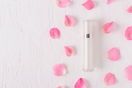 Top view of cosmetic bottle containers with pink rose petals on white background.の写真素材