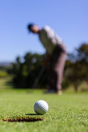 Golfer putting golf ball into hole