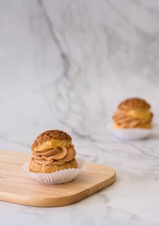 Homemade choux cream or cream puffs with tea cream on wooden