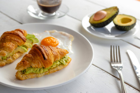 Croissant sandwich with egg,avocado on white dish and honey, coffee. breakfast and healthy food concept.の写真素材