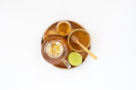 Top view of a cup of tea with ginger root, lime, cinnamon and teapot on white background. Health drink conceptの写真素材