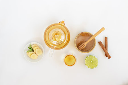 Top view of a cup of tea with ginger root, lime, cinnamon and teapot on white background. Health drink conceptの写真素材