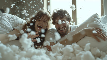 A couple shares a moment of pure joy and playful affection during a pillow fight, with feathers floating around in a cozy bedroom setting.の素材
