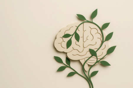 A mental health awareness concept with paper brain and green leaves symbolizing growth and healing in calm beige background for wellness and careの素材