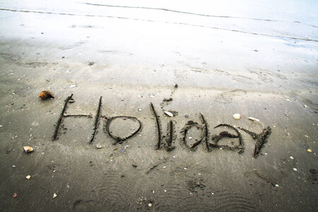 Holiday written in sand.の写真素材