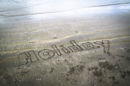 Holiday written in sand.の写真素材