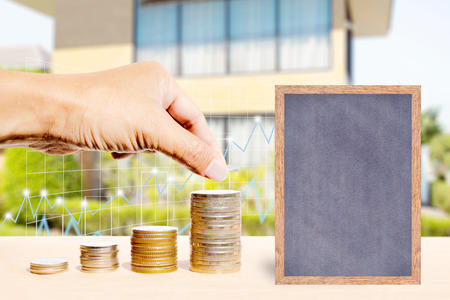 Business finance and real estate concepts, Hand stacking coins, Chalkboard free space for you planing, Business graph and blurred home garden background.の写真素材