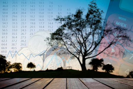 Double exposure of money coins for finance and banking concept, Empty wood table top on blurred images black tree silhouettes for background.の写真素材
