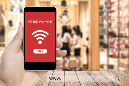 Hand holding smart phone with mobile payment and www. search bar over blur people in the shopping mall background, business and financial concept.の写真素材