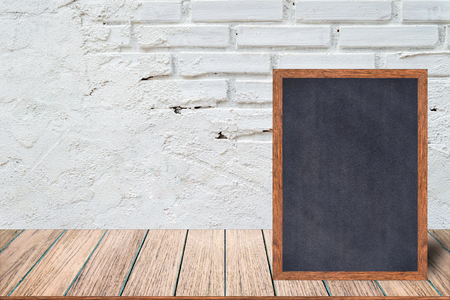 Chalkboard wood frame, blackboard sign menu on wooden table and with brick background with copy space, Template mock up for adding your design and leave space beside frame for adding more text.の写真素材
