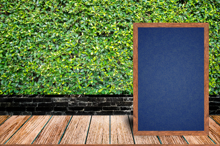 Chalkboard wood frame, blackboard sign menu on wooden table and grass wall background with copy space, Template mock up for adding your design and leave space beside frame for adding more text.の写真素材