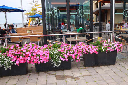 People eating, drinking and relaxing outside restaurant near harbourのeditorial素材