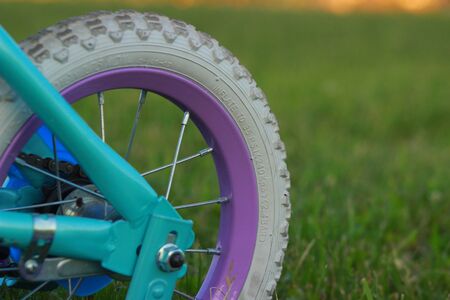 Children bicycle wheel on green grass, close up photoの写真素材