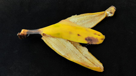 Banana peel on black background. Close-up of a ripe yellow banana.の写真素材