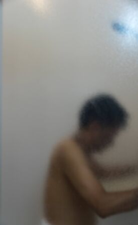 Mature man having bath in the bathroom with  frosted glass foregroundの写真素材