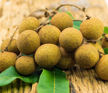 Fresh ripe longan fruits and leaves on a wooden boardの写真素材