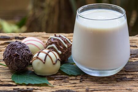 Four pieces of Chocolate and milk is placed on a wooden board.の写真素材