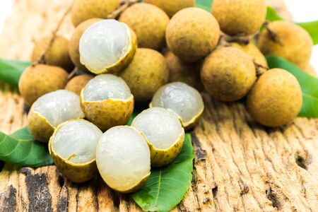 Fresh ripe longan fruits and leaves on a wooden board