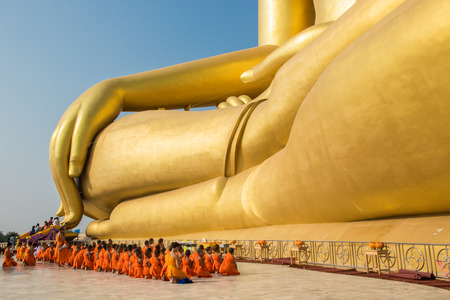 Priests and seminarians and people pray to big golden buddha on blue sky in Angtong, Thailandのeditorial素材