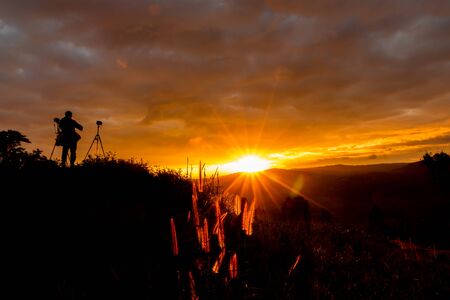 silhouette of photographer on beautiful  sunrise and beautiful sky in the mountain at Loei Provice,Thailand.の写真素材