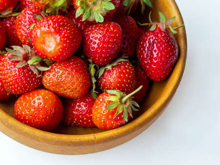 strawberries on a wooden plate, isolated white backgroundの写真素材