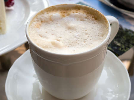 A large cup of coffee with frothed milk in the garden on a sunny dayの写真素材