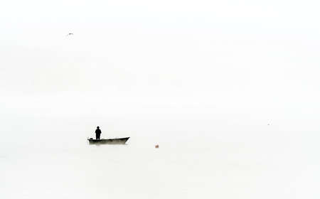 A fisherman in a boat on a foggy morning on Lake Zywieckie. South Polandの写真素材