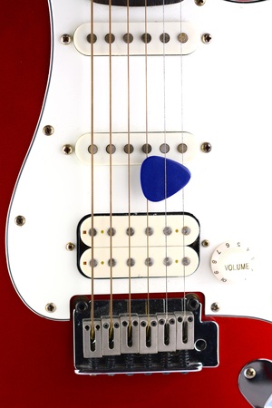 Red electric guitar with pick on white の写真素材
