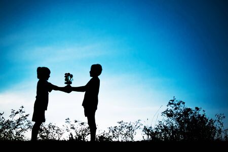 Little girl give a flower to little boy, Silhouette conceptの写真素材