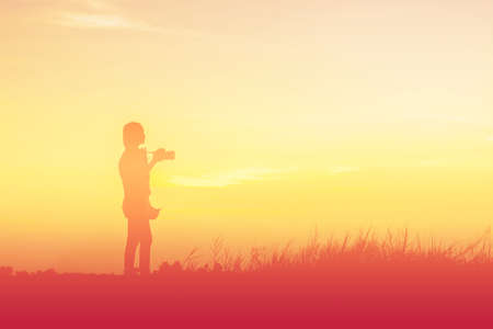 Silhouette woman photographer at sunsetの写真素材