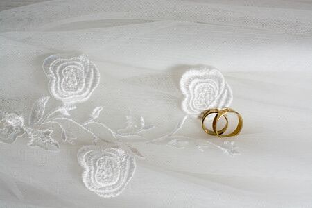 Two wedding rings laying on wedding dressの写真素材